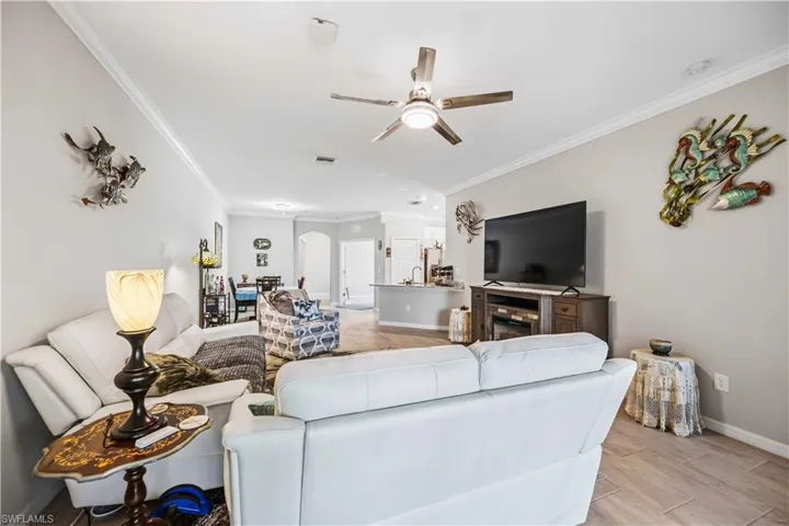 Living area with ornamental molding, ceiling fan, wood tiled floors, arched walkways, and a fireplace