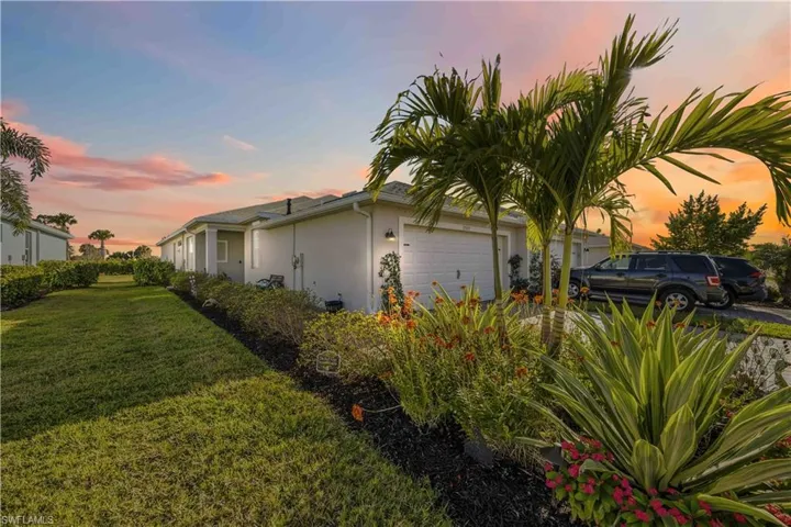 View of property exterior with stucco siding, a garage, and a lawn