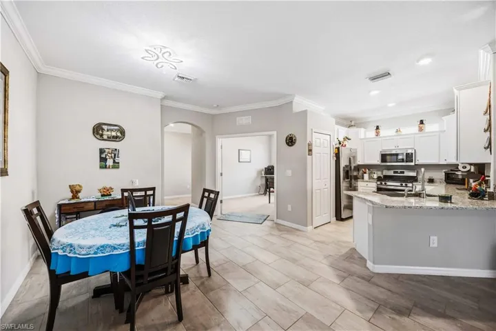 Dining space with arched walkways, crown molding, and wood finish floors