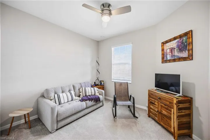 Carpeted living room with baseboards and a ceiling fan