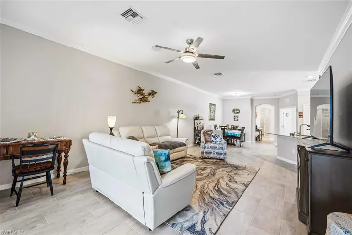 Living room with crown molding, a ceiling fan, and arched walkways