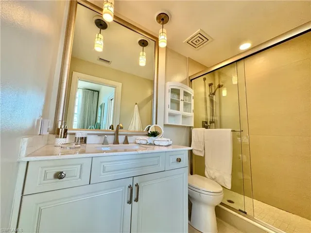 Bathroom featuring a shower with door, vanity, and toilet