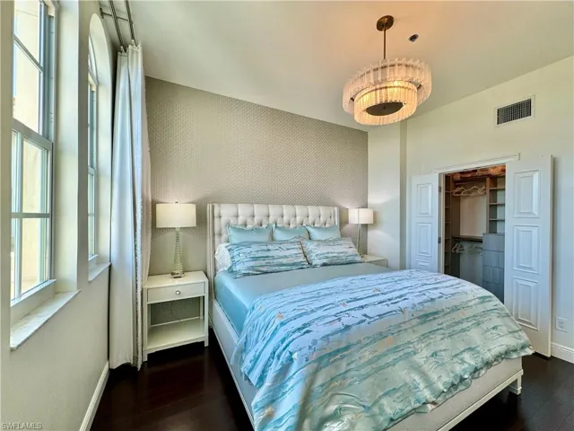 Bedroom with a walk in closet, a closet, and dark wood-type flooring