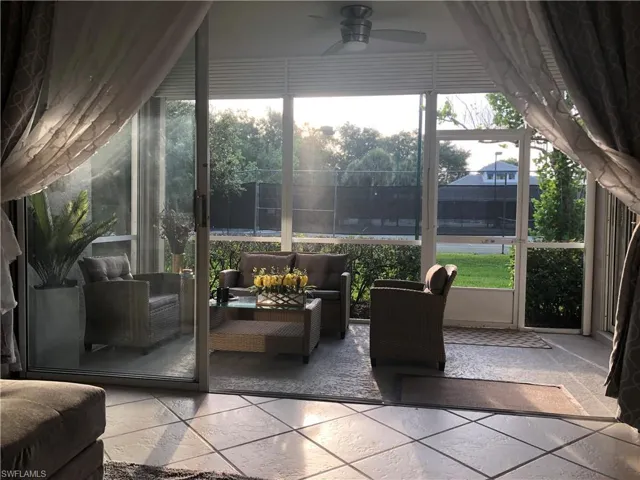 Expansive screened lanai featuring tile flooring, a ceiling fan, and sliding glass doors