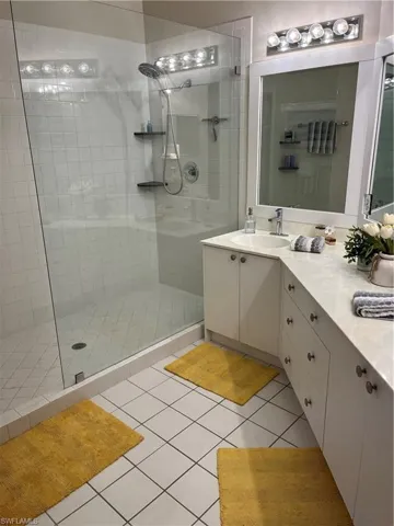 Bathroom featuring a glass-enclosed shower with white tiled walls and a dual-head shower system