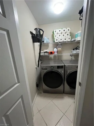 Laundry area featuring tile flooring, neutral wall paint, overhead lighting, and wire shelving