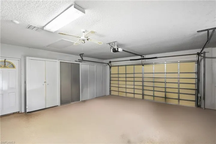 Garage space with a ceiling fan, fluorescent lighting, and multiple storage doors