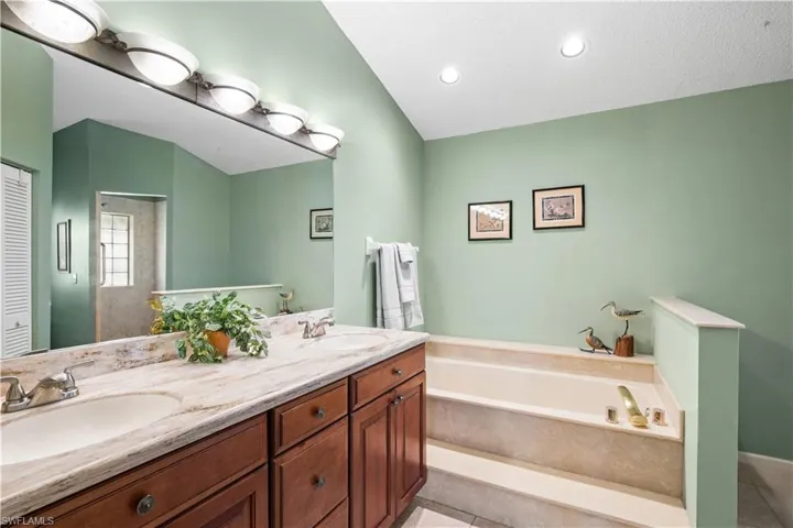Dual vanity with undermount sinks, wood-finish cabinetry, and a large mirror with integrated lighting