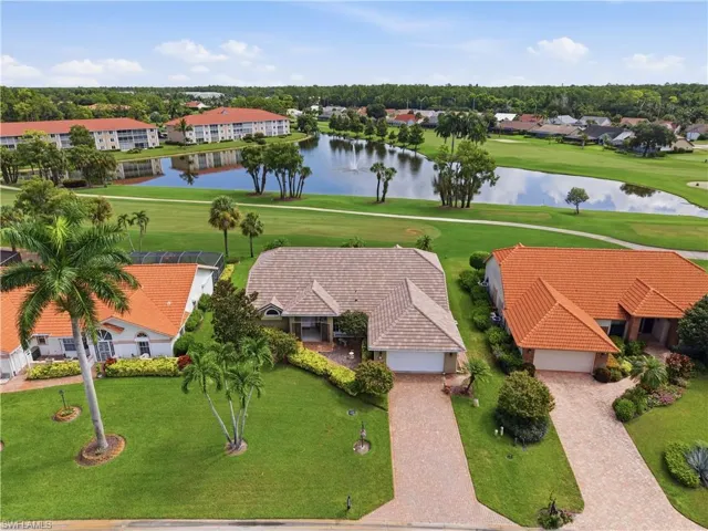 Mature landscaping, paver driveway, shingle roof, integrated garage, and a waterfront golf course setting