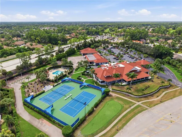 Clubhouse with a red tile roof and expansive parking area
