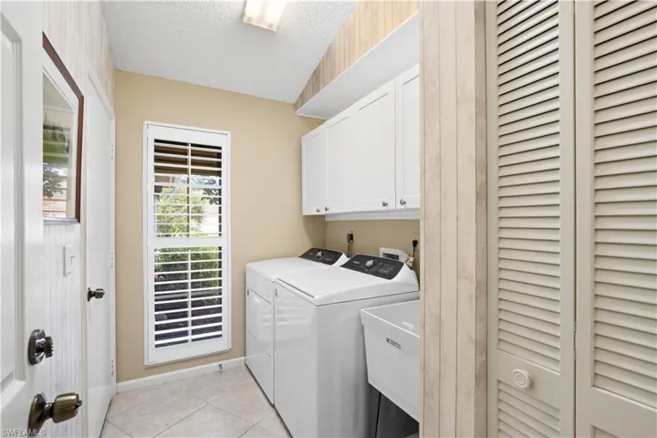 Laundry area featuring white cabinetry, a utility sink, and tile flooring