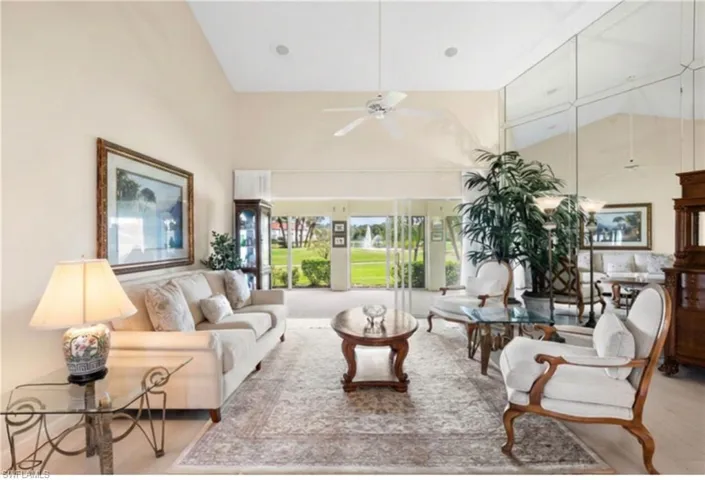 Vaulted ceiling with a ceiling fan, wall-to-wall mirrored accent wall, and expansive glass sliding doors