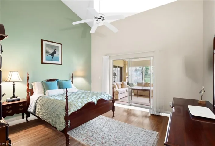 Vaulted ceiling, ceiling fan, wood-finish flooring, sliding glass door, and a built-in wall niche