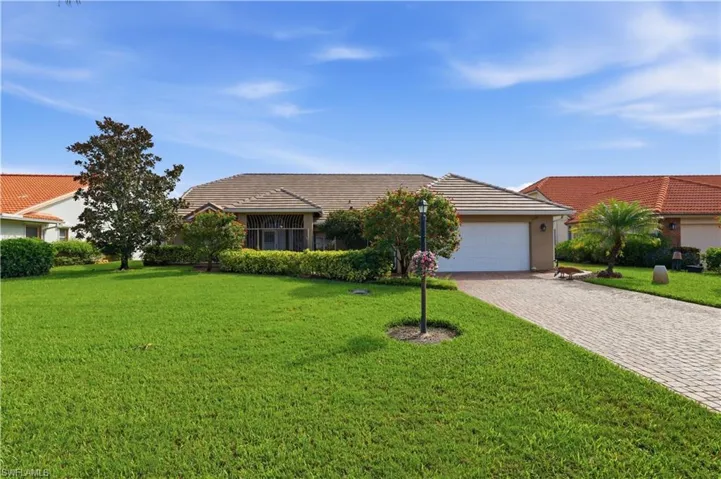 Paved driveway, attached garage, well-maintained lawn, mature landscaping, and screened enclosure