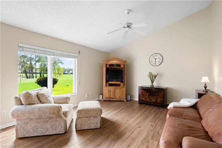 Vaulted ceiling, ceiling fan, wood-finish flooring, large window, expansive green landscape