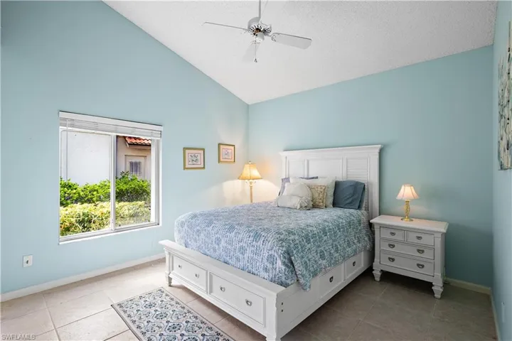 Vaulted ceiling, ceiling fan, sliding window, tile flooring, built-in storage bed frame
