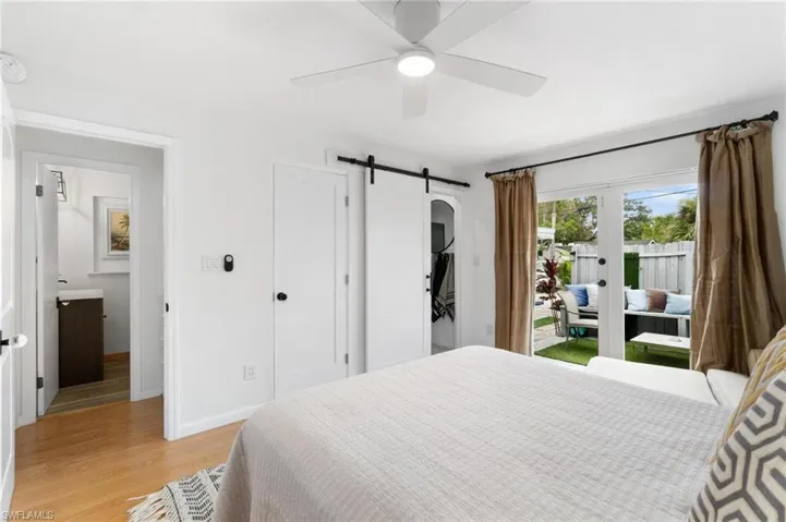Bedroom with a barn door, access to outside, ceiling fan, and light hardwood / wood-style flooring
