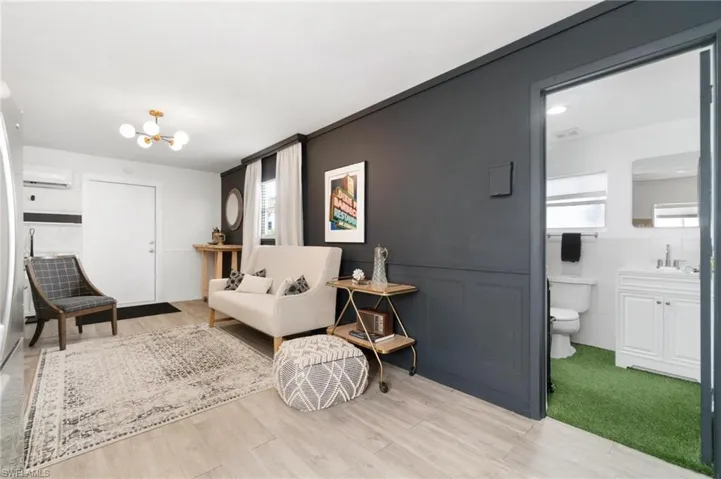 Living room with a healthy amount of sunlight, a wall mounted AC, a chandelier, and light hardwood / wood-style floors