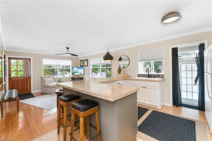 Kitchen featuring hanging light fixtures, ornamental molding, white cabinets, and light wood-type flooring