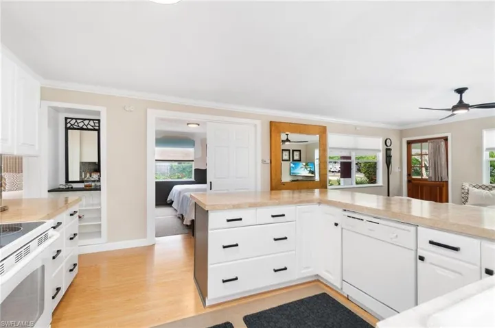 Kitchen featuring white dishwasher, light hardwood / wood-style floors, stove, white cabinets, and ceiling fan
