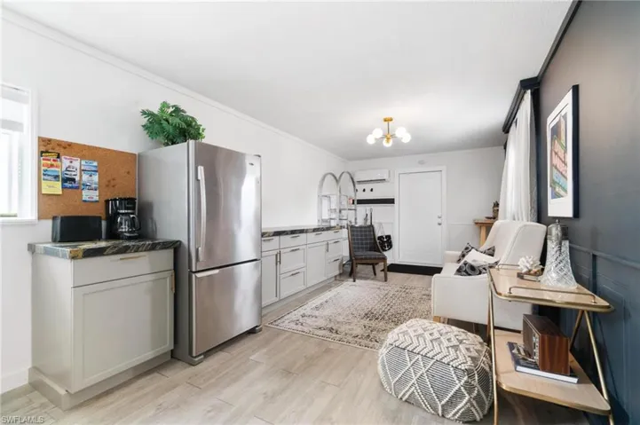 Kitchen with light hardwood / wood-style flooring, a wall mounted air conditioner, an inviting chandelier, ornamental molding, and stainless steel refrigerator