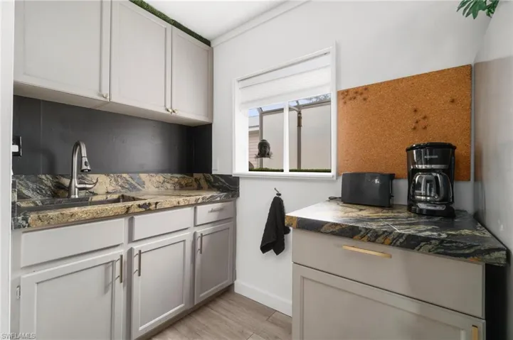 Kitchen featuring dark stone counters, sink, and light hardwood / wood-style flooring