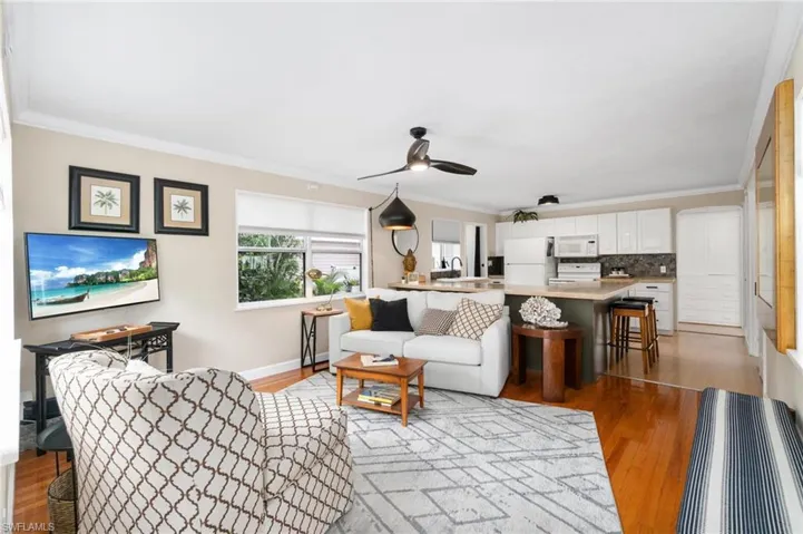 Living room with sink, ceiling fan, light wood-type flooring, and crown molding