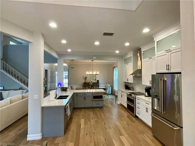Kitchen with upgraded Cafe stainless steel appliances, white cabinets, quartz countertops, and glass insert cabinets