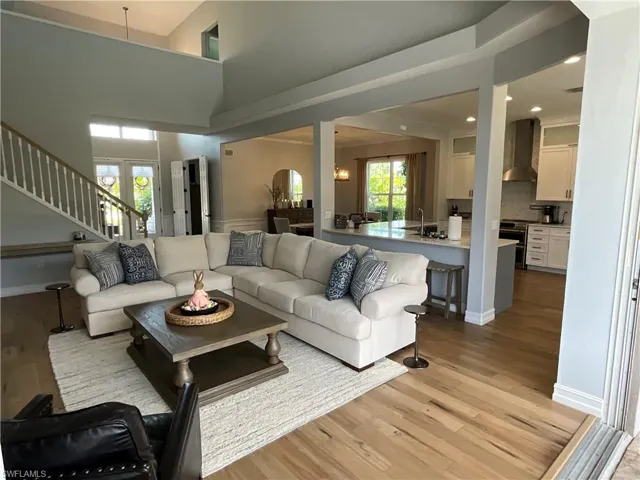 Living area featuring baseboards, stairway, a high ceiling, light wood-type flooring, and recessed lighting