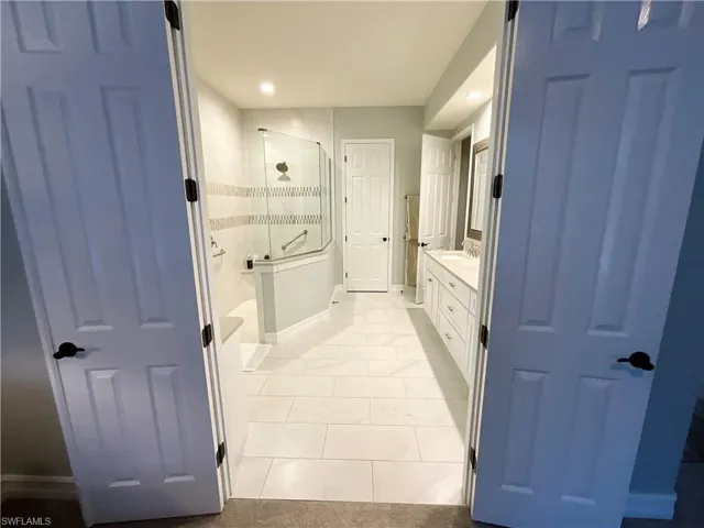 Master Bathroom with Remodeled master bath features recess lighting, french doors, a walk in shower, double sinks and separate “her” vanity