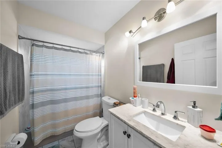 Bathroom with curtained shower, toilet, and vanity