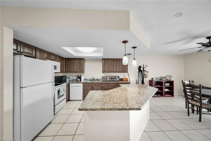 Kitchen featuring white appliances, pendant lighting, light tile patterned floors, sink, and ceiling fan
