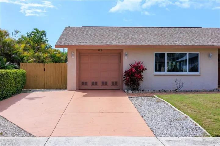 View of front facade with stucco siding, an attached garage, driveway, roof with shingles, and a gate