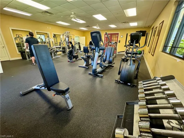 Gym with a drop ceiling, visible vents, a ceiling fan, and baseboards
