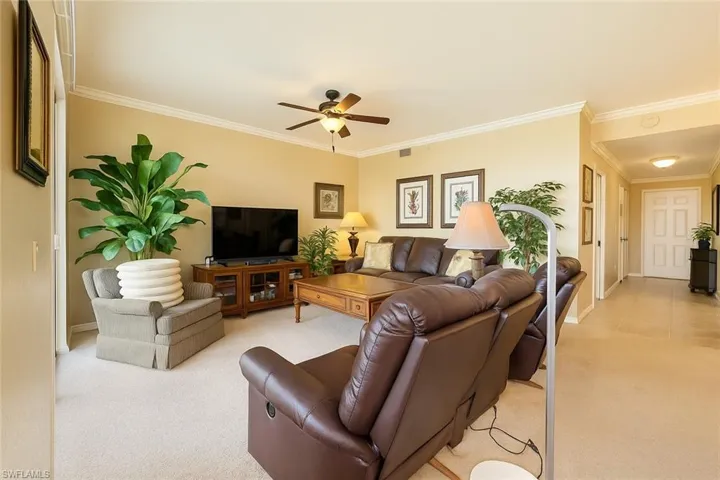 Living room with light carpet, crown molding, and ceiling fan