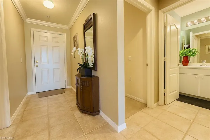 Foyer featuring light tile patterned flooring and crown molding