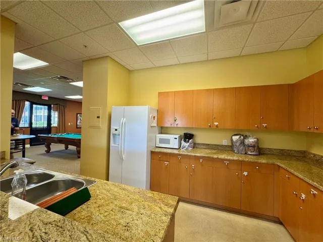 Kitchen with pool table, white appliances, brown cabinets, and a sink