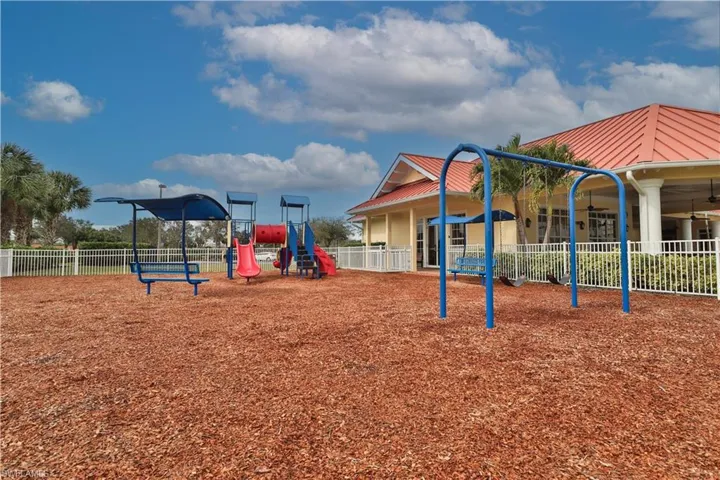 Outdoor playground area featuring a swing set, slide structure, and bench seating