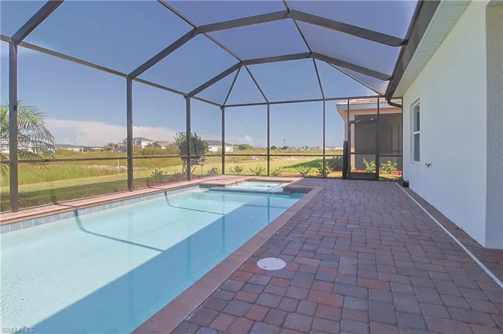 Screened lanai featuring a swimming pool, integrated spa, and paver decking