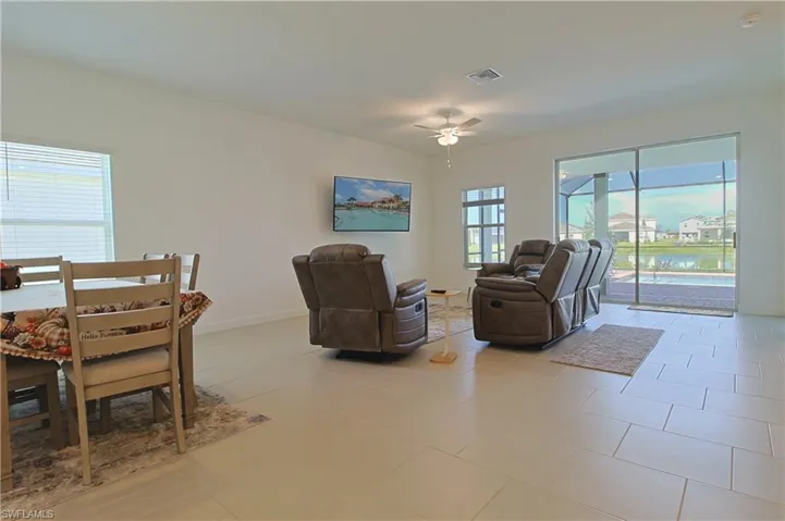 Open-concept living space with large format tile flooring, ceiling fan, and sliding glass doors
