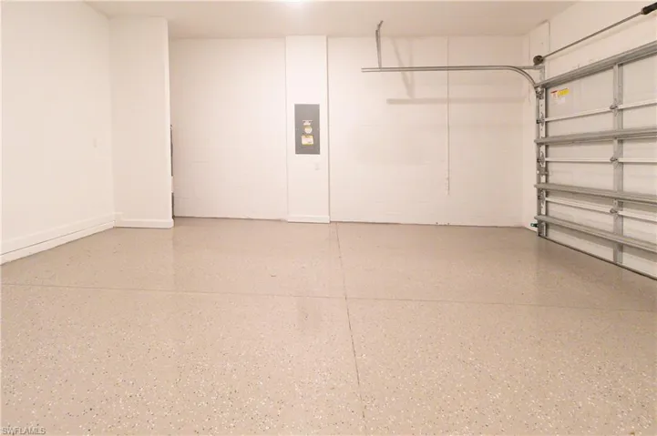 Spacious garage featuring a durable speckled epoxy floor, white walls, and a visible garage door mechanism