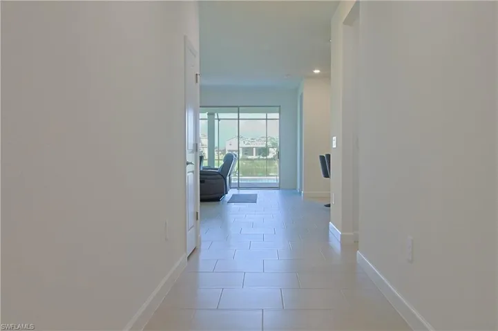 Recessed lighting illuminates the hallway with light-toned tile flooring