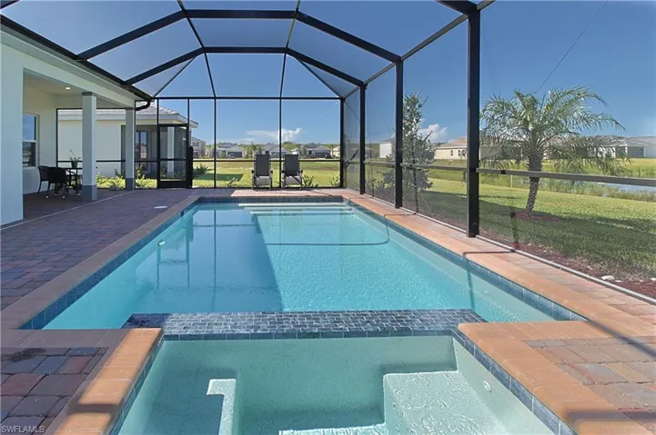 Screened pool enclosure with an integrated spa, brick paver decking, and a covered lanai