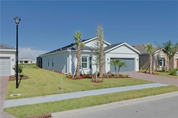 Contemporary single-story residence featuring a two-car garage, pitched roofline, and landscaped front yard with palm trees
