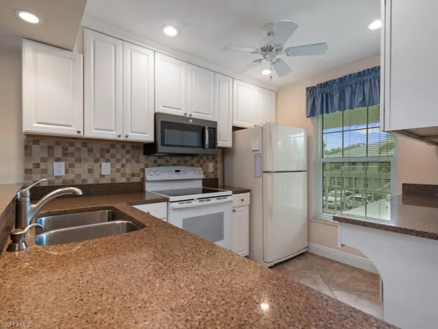 Kitchen featuring white cabinetry, white appliances, sink, and backsplash