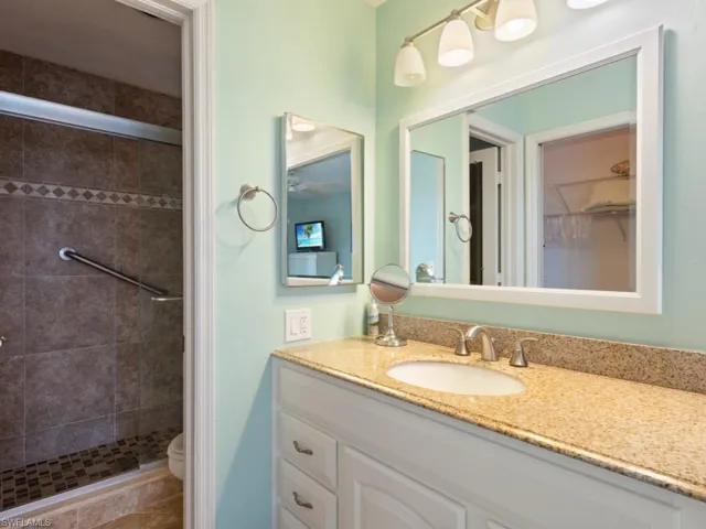 Bathroom featuring a shower with door, vanity, tile patterned flooring, and toilet