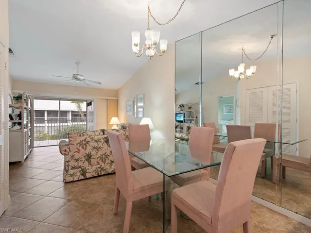 Tiled dining space with ceiling fan with notable chandelier and high vaulted ceiling