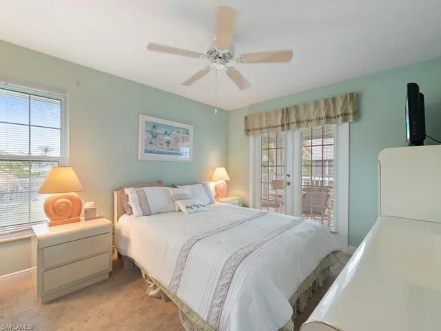 Carpeted bedroom featuring multiple windows, access to outside, and ceiling fan