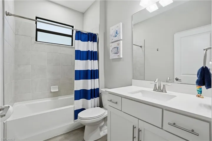 Full bath featuring vanity, shower / bath combo, and light wood finished floors