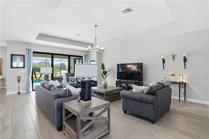 Living area featuring a tray ceiling, hanging lights, and wood finish floors
